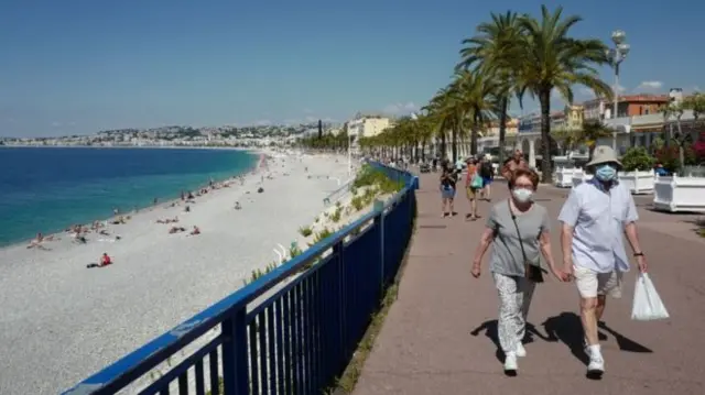 People walk along a beach in France