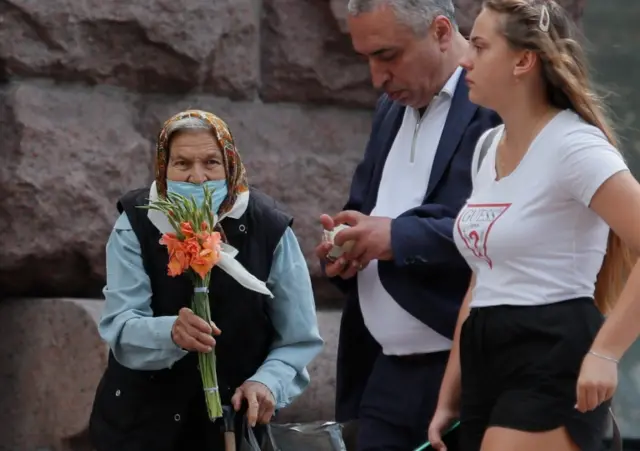 Woman in mask in Kyiv selling flowers