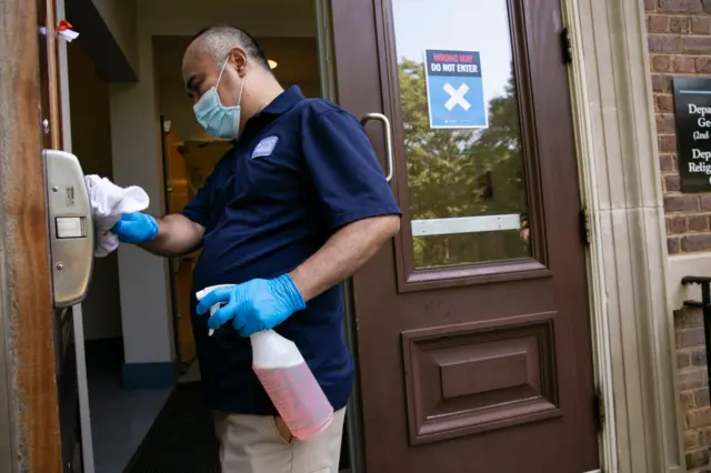 A member of staff disinfects a door handle at the University of North Carolina at Chapel Hill