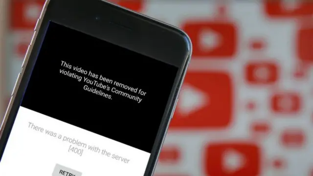 A photo illustration shows the YouTube app on a mobile phone with the message that the video has been taken down