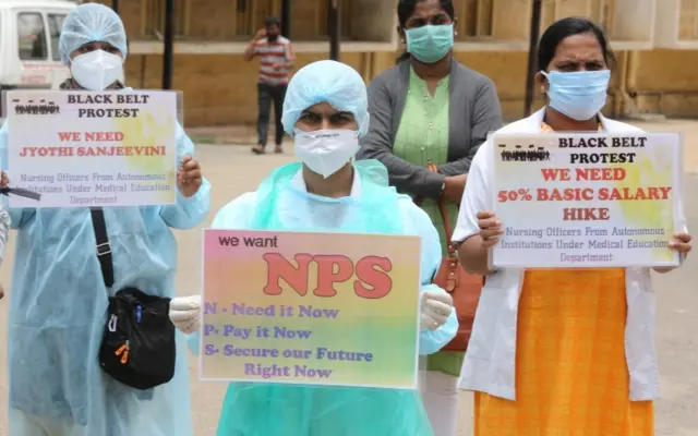 Members of nursing and medical staff of Bowring Hospital tie black ribbon as they hold placards during the silent protest, in Bangalore, India