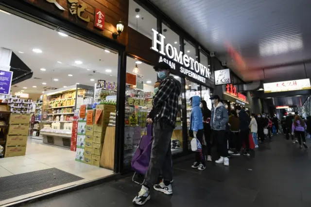 People line up to enter a supermarket hours before a citywide curfew is introduced in Melbourne