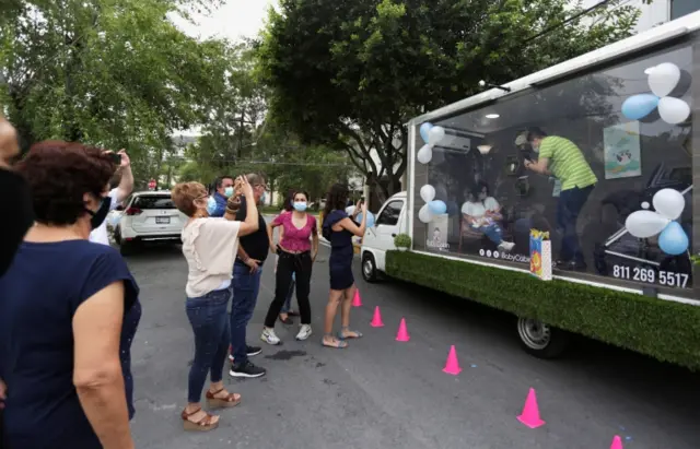 A couple is pictured by relatives inside a sanitized cabin called "Baby Cabin Parade" in Mexico