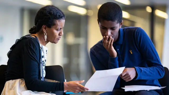 Joshua Fessahaye looks over his GCSE results with his mother at Ark Evelyn Grace Academy, London