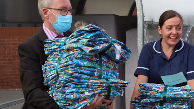 Staff carrying piles of rainbow scrubs