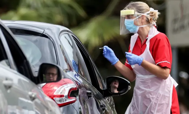 A medical worker takes a swab sample in a drive-through testing centre