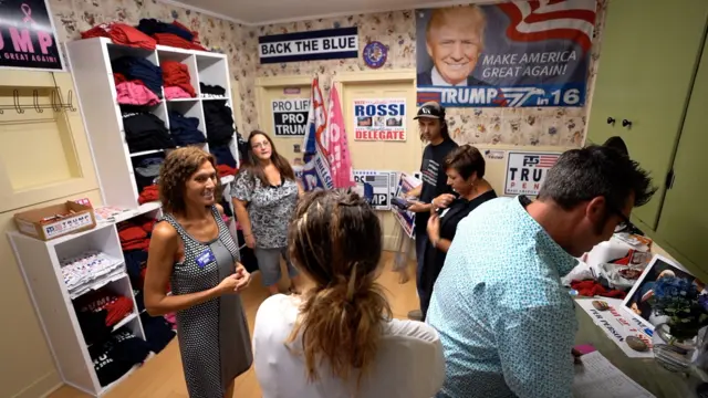 Campaign workers gather to talk, surrounded by Trump merchandise