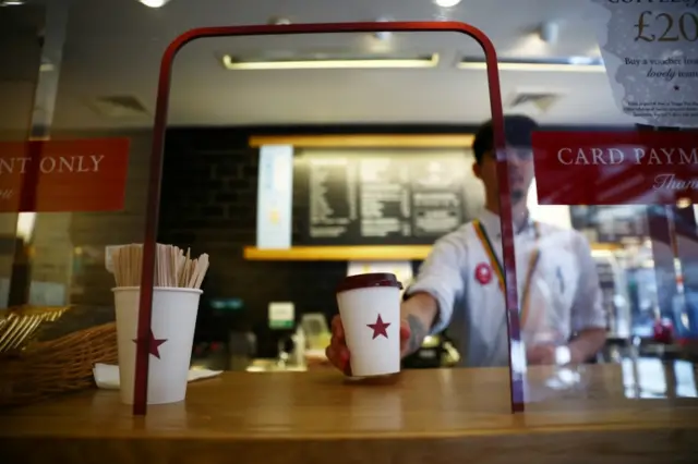 A coffee is passed to a customer at Pret a Manger in London