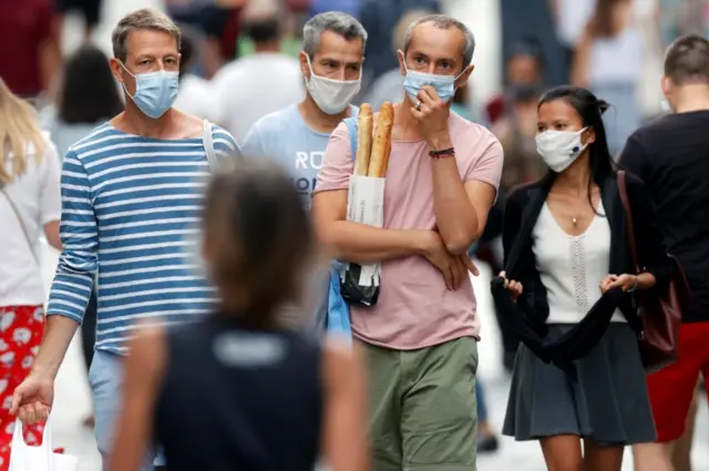 People wearing protective masks walk in the Montorgueil street  in Paris