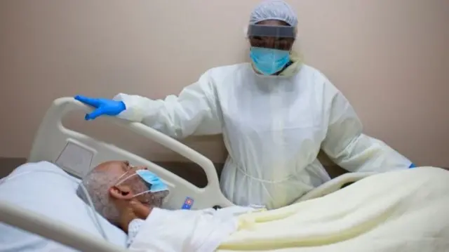 A doctor looks over a patient lying in a hospital bed