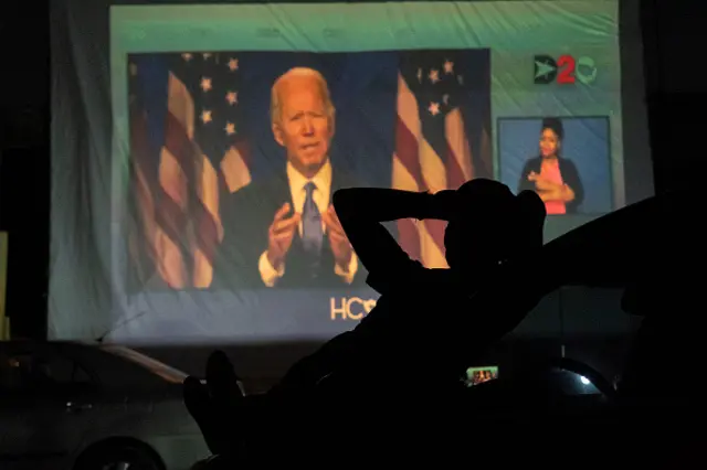 A Joe Biden supporter watch DNC as Joe Biden appears on a large screen during a drive-in DNC watch event on August 20, 2020 in Houston, Texas