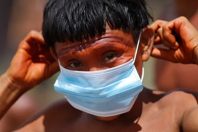 A man from the indigenous Yanomami ethnic group holds a protective face mask