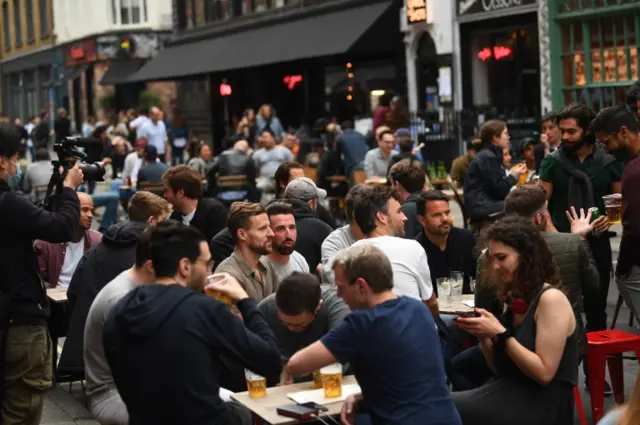 Young people drinking at tables outside a pub