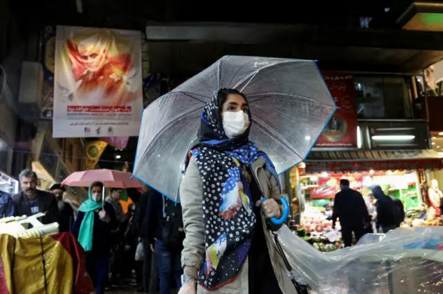 An Iranian woman wears a protective face mask and gloves