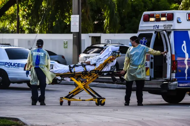 Medics transfer a patient on a stretcher from an ambulance outside of Emergency at Coral Gables Hospital where Coronavirus patients are treated in Coral Gables near Miami, on July 30, 2020