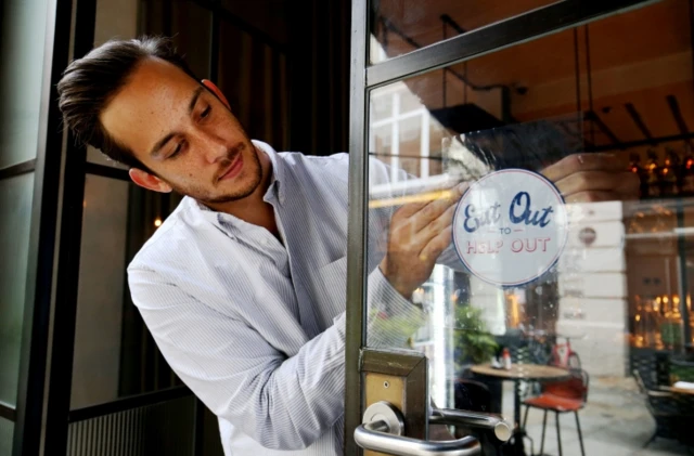 A restaurant manager applies a deal notice to a window