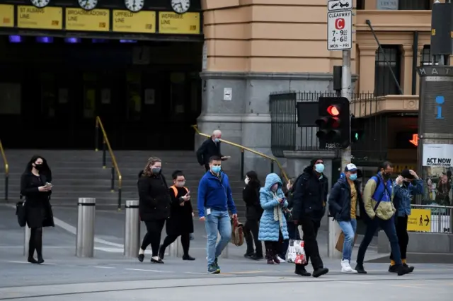 Pedestrians wearing masks walk from Flinders Street station in Melbourne