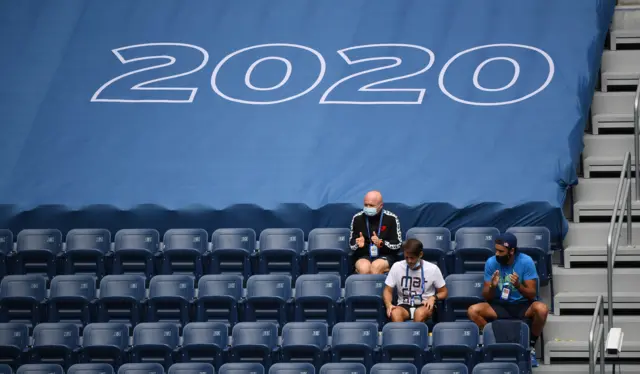 Coaches and staff sit in empty seats as spectators