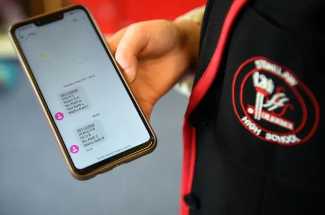 A pupil checks his results on a mobile