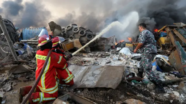 Firefighters spray water at a fire following an explosion in Beirut's port area