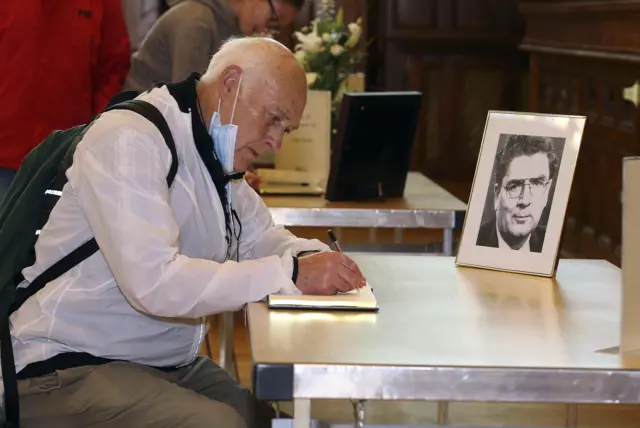 man signing condolence book for john hume