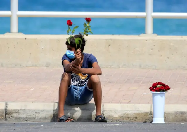 A street vendor wearing a mask sells roses amid the coronavirus pandemic