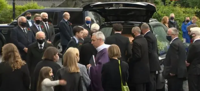 John Hume's coffin being place in a hearse