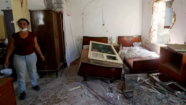 A woman stands inside her damaged home following Tuesday's blast in Beirut's port area, Lebanon