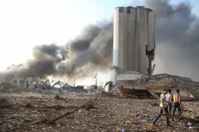 Young men walk past a destroyed grain silo following an explosion at the Beirut Port, Beirut, Lebanon (4 August 2020)