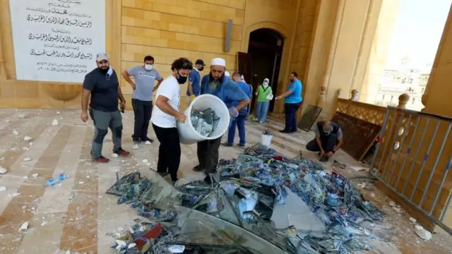 Men remove broken pieces of glass in a mosque damaged in Tuesday's blast in Beirut, Lebanon