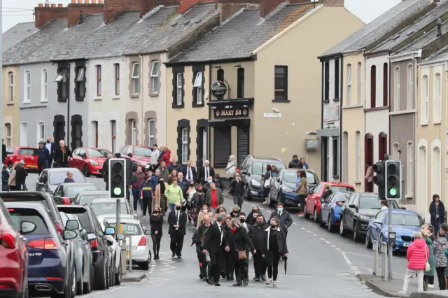 Mourners follow the funeral cortege along the Lone Moor Road in Derry
