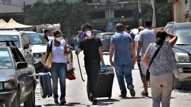 People walk with their belongings after evacuation from their damaged housing