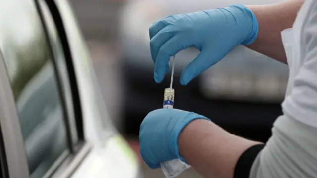 A test sample is held at a COVID-19 testing centre