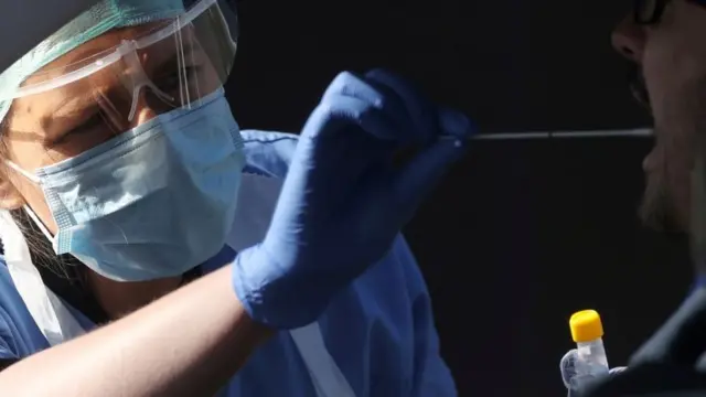 A member of medical staff takes a swab from a person in a car