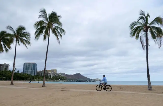 A cyclist rides along an empty Waikiki Beach as Hurricane Douglas veers northward sparing Oahu from a direct hit, in Honolulu, Hawaii, on July 26, 2020
