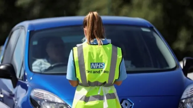 An NHS employee stands in front of a car at a testing centre