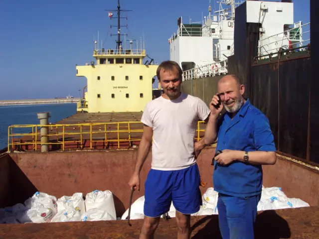 Boris Prokoshev (R), captain of cargo vessel Rhosus, and boatswain Boris Musinchak pose next to a freight hold loaded with ammonium nitrate in the port of Beirut, Lebanon - summer 2014.