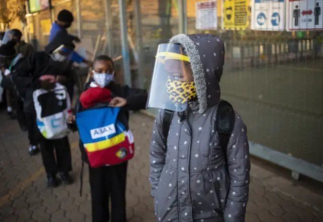 Children wait outside the school gate while wearing protective clothing in the form of masks and face shields as part of their safety due to the Covid-19 coronavirus pandemic, in Johannesburg, South Africa, on 13 August 2020