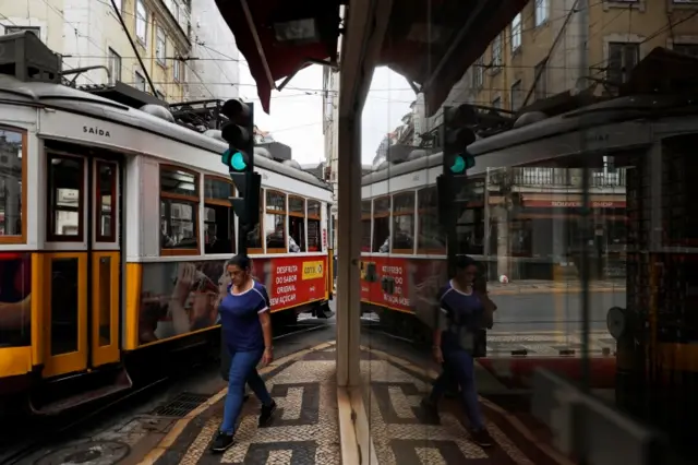 A woman walks next to a tram in Lisbon, Portugal. File photo