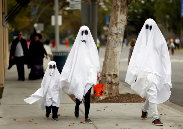 People wear fancy dress costumes while trick or treating