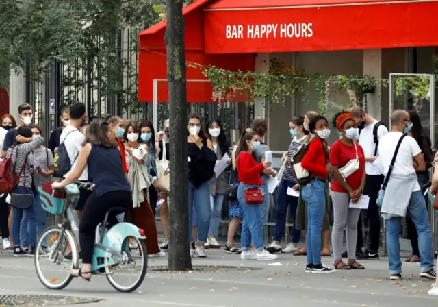 People wearing masks stand outside a restaurant