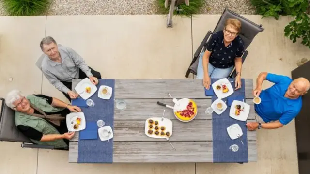 A group of four people eat a meal outside together