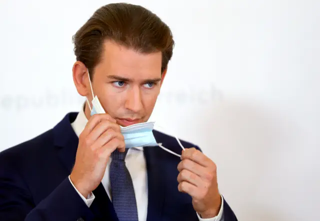 Austrian Chancellor Sebastian Kurz takes off a protective face mask as he arrives for a news conference about coronavirus