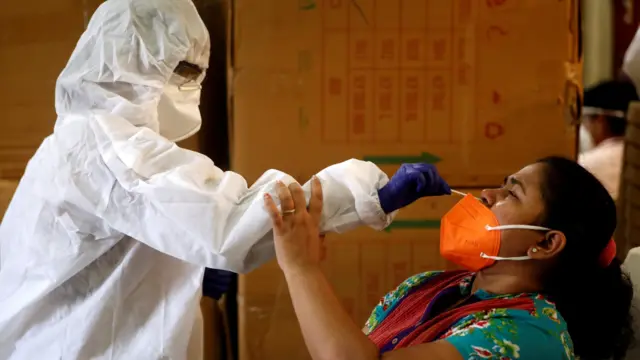 A health worker conducts a coronavirus test on a woman in Mumbai, India