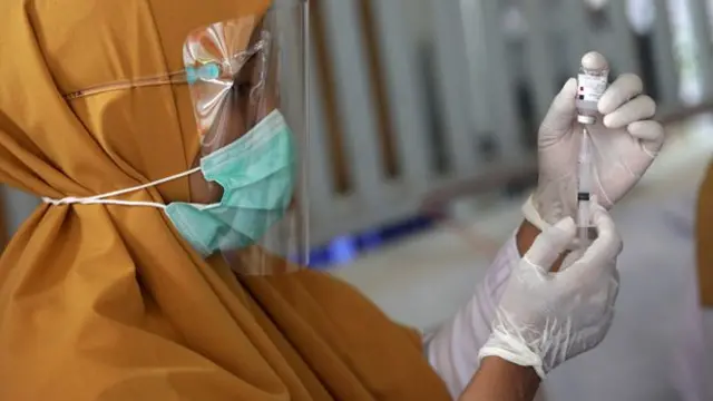 A person in PPE prepares a vaccine