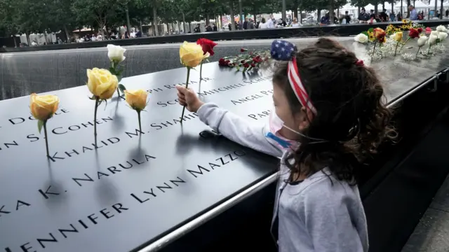 A girl places a flower on the edge of the North pool during ceremonies on the 19th anniversary of the September 11, 2001 attacks