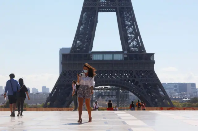 A woman stands in front of the Eiffel Tower