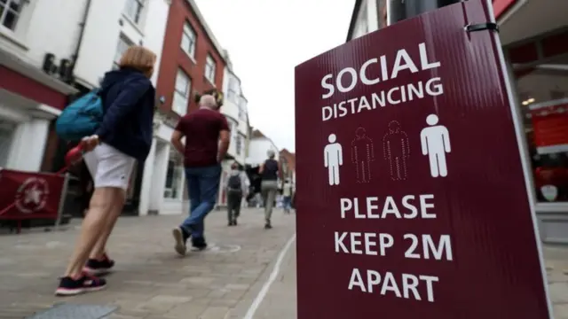 People near social distancing signs