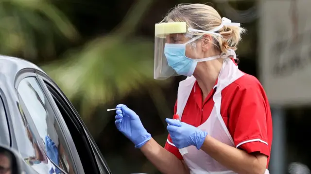 A medical worker takes a swab sample in a drive-thru testing centre