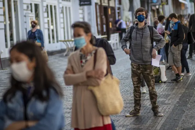 People wearing protective face masks wait in line at a coronavirus testing station in Prague